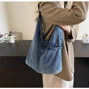 Detail of soft washed blue denim tote bag featuring a front pocket and integrated strap
