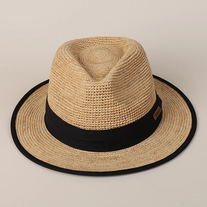 Close-up of woven straw hat featuring black ribbon and handmade logo label detail