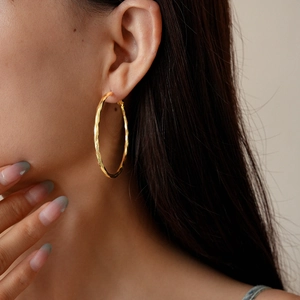 Close-up of 14k gold plated twisted hoop earrings on model highlighting hammered texture