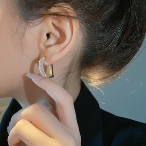 Elegant gold C-shaped hoop earrings with zircon micro-paving on a minimalist dark backdrop