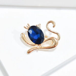 Détail d'une broche chat dorée élégante avec une grande pierre précieuse bleu foncé ovale