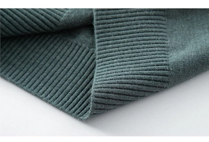 Detailaufnahme des dunkelgrünen Strickgewebes mit feiner Textur und Rippbündchen