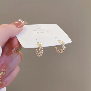 Detailed shot of elegant pearl hoop earrings with gold metal accents on a display card