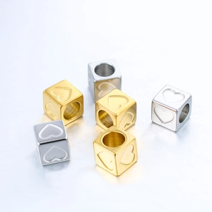 Detailed view of 6mm gold and silver stainless steel cube beads with engraved heart patterns
