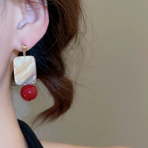 Model wearing square shell and red bead dangle earrings with gold-tone finish