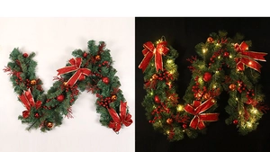Detail of green Christmas garland with red bows, berries and warm LED lights