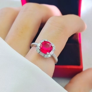 Close-up of luxury 2-carat red ruby ring with sparkling zircon halo on finger