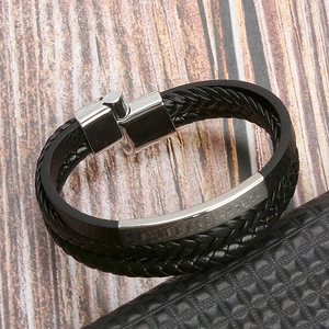 Handmade black woven leather bracelet with silver magnetic metal clasp on wooden desk