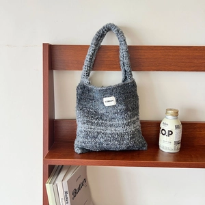 Minimalist gradient knit tote bag in grey melange with woven texture on a wooden shelf