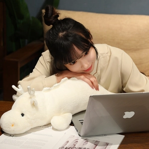 Detail of soft plush dragon doll used as a cozy pillow in a warm home office setting