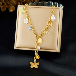 Dettagli di una collana dorata con pendenti a farfalla, fiori, perle e gemme preziose