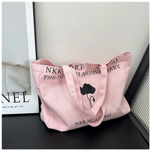 Close-up of pink canvas tote bag featuring black floral print and artistic lettering