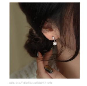 Detailed close-up of a French style pearl drop earring with sparkling diamond accents