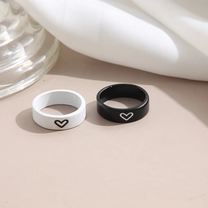 Minimalist black and white heart couple rings set in matte finish on soft fabric