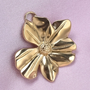 Macro detail of a 304 stainless steel flower pendant in gold finish on pink satin fabric