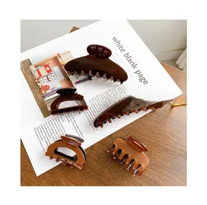Set of amber acetate hair claws in various sizes on a minimalist magazine background