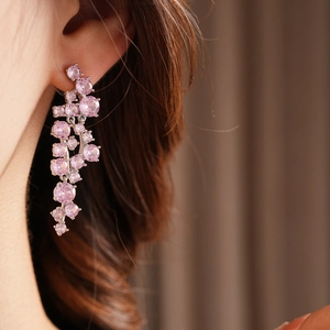 Close-up of long pink zircon tassel earrings on a model with silver plating details