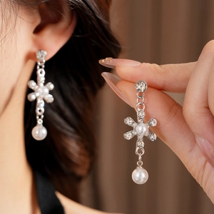 Detail of silver drop earrings with floral rhinestones and pearls on model