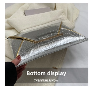 Detail view of silver crocodile embossed envelope clutch with metallic trim and structure