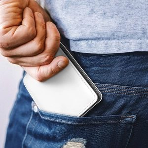 Close-up of a white leather wallet being pulled from a denim jeans back pocket