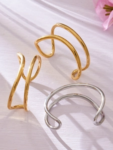 Dettaglio dei bracciali aperti a doppio strato a forma di onda in oro e argento