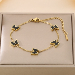 Detail of gold butterfly bracelet with black enamel charms on champagne jewelry display