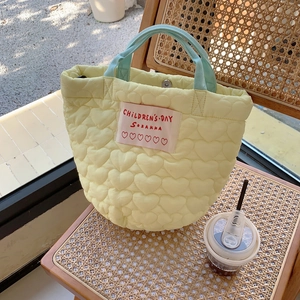 Détail du sac à main jaune matelassé avec anses bleu clair sur une chaise en bois