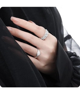 Detail showing irregular textured silver rings with blue gemstone on black silk background
