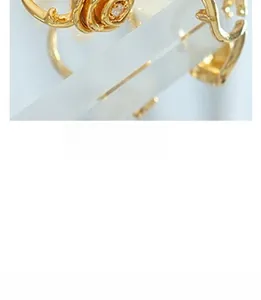 Close-up of golden rose-shaped ring with center crystals on clear acrylic stand