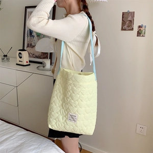 Detail of light yellow quilted tote with heart patterns and blue shoulder strap