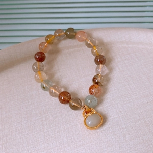 Macro shot of natural crystal beads with white jade Ruyi pendant on beige fabric
