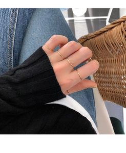 Detail view of minimalist gold stacking rings set worn in a stylish casual lifestyle setting