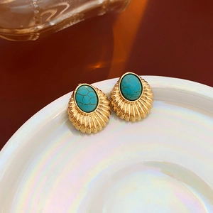 Detail of vintage gold stud earrings with turquoise oval stones on a white ceramic tray