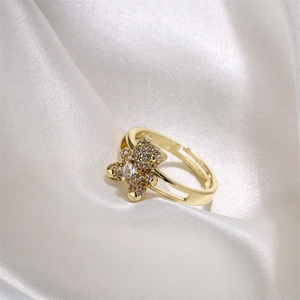 Close-up of golden teddy bear ring with pavé zircons on white silk background