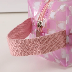Detail of pink heart-patterned mesh pencil case showing fabric strap and metal zipper