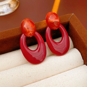 Detailed view of red oval hollow drop earrings on a premium jewelry display case