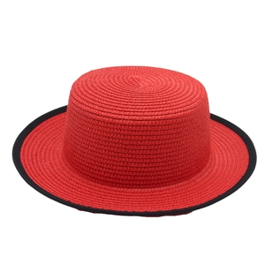 Detailed top view of red straw boater hat with black trim and fine woven texture