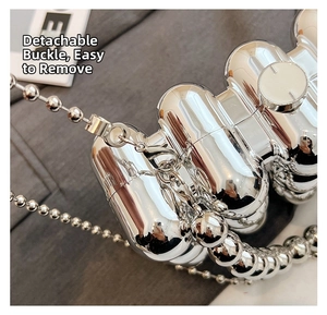 Macro detail of a silver acrylic box bag featuring a detachable buckle and metal bead chain