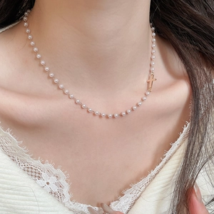 Detail shot of a pearl necklace with golden cross on a lace collar model's neck