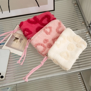 Detailed view of plush heart-patterned makeup bags in pink and beige on a stylish shelf