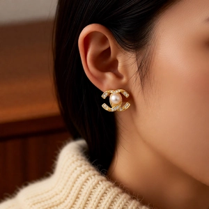 Close-up of pearl flower stud earrings with 14k gold plating and rhinestones on model