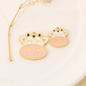 Detail of gold cow charms with white enamel and pink noses in a white ceramic dish
