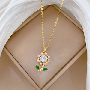 Close-up of golden flower necklace with pearls and green gems in a jewelry box