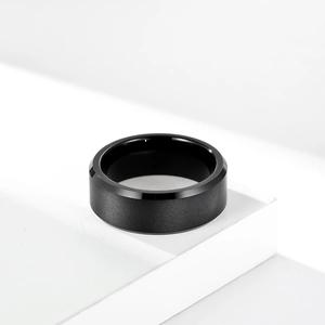 Minimalist brushed matte black tungsten ring displayed on a modern white geometric stand