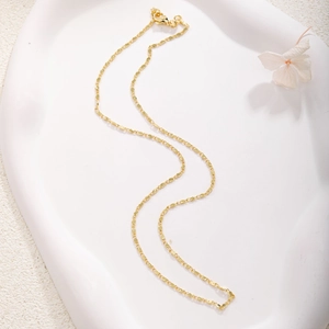Detail of gold-plated flat link chain necklace with secure lobster clasp on tray