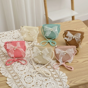 Detailed view of handmade woven straw mini bags with lace bows and pearl accents