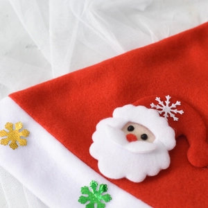 Detailed close-up of a red felt Christmas hat with Santa appliqué and sparkly gold sequins