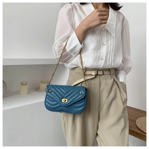 Blue V-quilted chain shoulder bag with gold turn-lock closure on model
