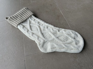 Detailed view of cream and gray knitted Christmas stocking with diamond cable patterns
