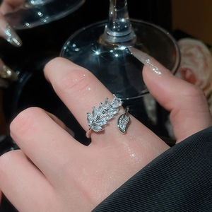 Close-up of zircon leaf ring with marquise-cut stones and a delicate dangling leaf